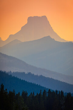 Mountain peaks silhouetted by vibrant orange sunset sky