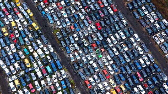 High angle perspective shot of car cemetery rows. Diagonal overhead view of various old and damaged automobiles parked closely in parallel lines.