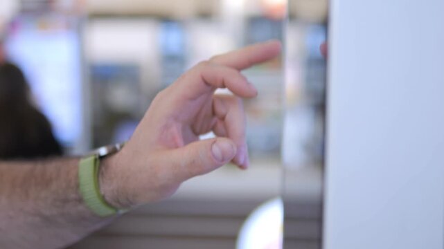 Hand taps screen. Person uses device. Blurred background shows modern setting. Focus on interaction. Ideal for tech, digital work, or user engagement themes