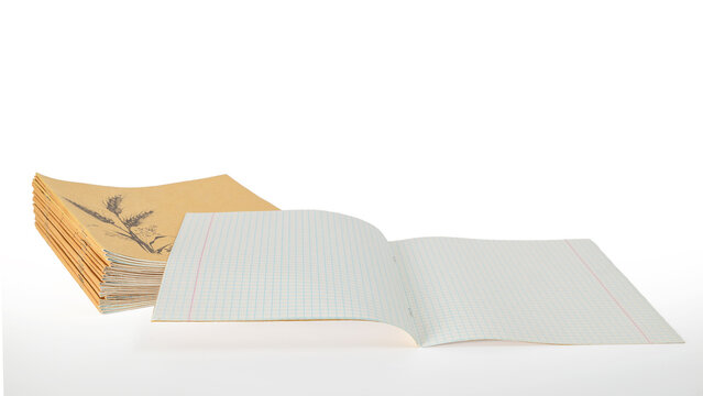 opened school notebook in a cage in front of a stack of craft notepads on a white background