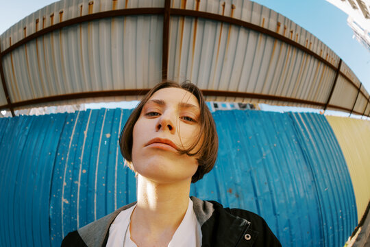 Young Person Poses Under Metal Structure on Sunny Day