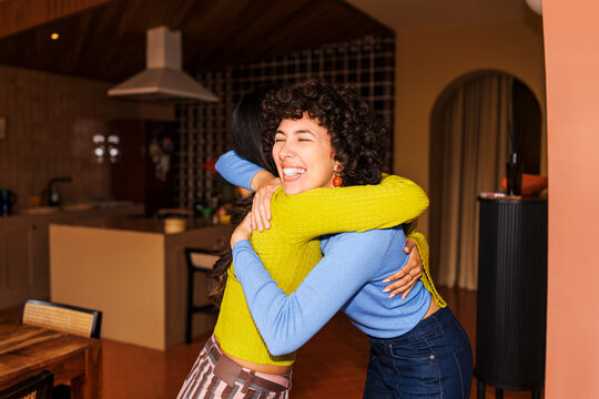 Friends sharing a happy embrace in home