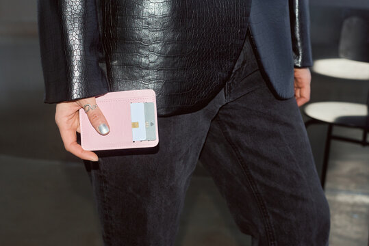 Person holding a pink wallet and standing in a modern space