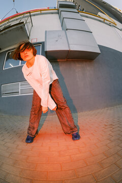 Young Person Poses on Street With Building in Background During Sunset