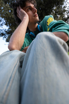 Young guy rests in Italy with backpack and trolley in the park