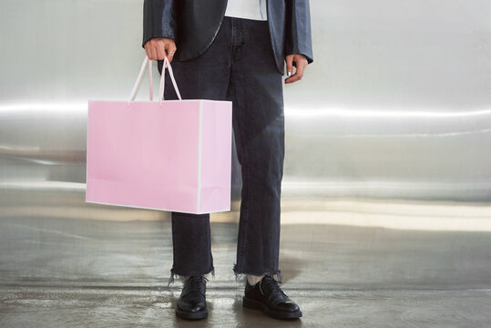 Woman stands with a pink shopping bag at a modern location