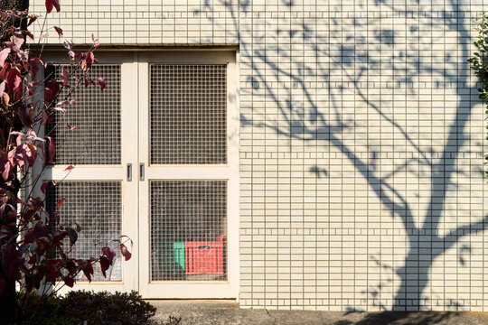 Sunlight and tree shadow on tiled wall with urban minimal background