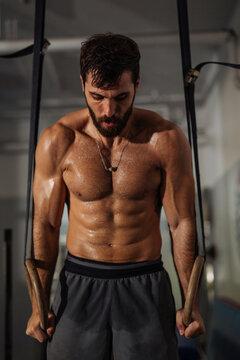 Muscular Man Training on Gym Rings in Intense Workout