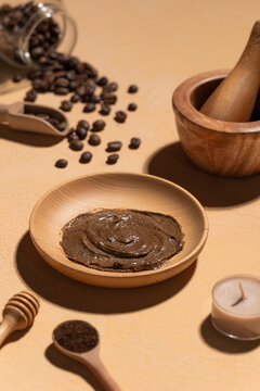 Homemade coffee scrub in a wooden bowl with scattered beanS