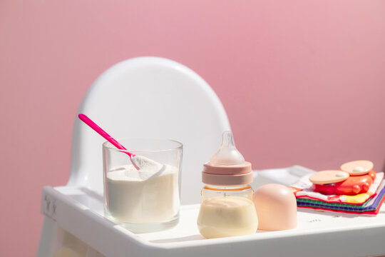 Baby feeding preparation with formula powder and bottle on a highchair