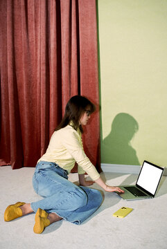 Woman Sitting on Floor Using Laptop with Smartphone Nearby