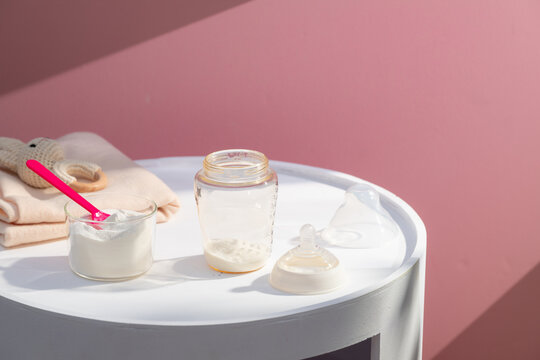 Preparing baby formula with powder and bottle on a white table
