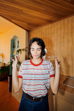 Woman making wish eyes closed at modern apartment