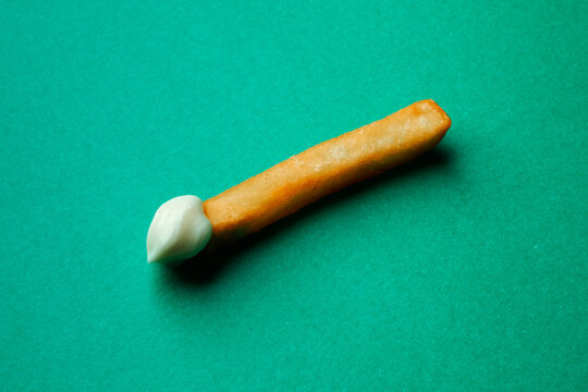 a french fry placed diagonally with mayonnaise on one end