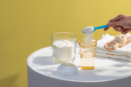 Preparing baby formula by adding powder from a scoop into a bottle