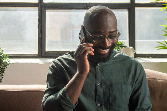 Smiling Man Talking On Phone At Home In Bright Room