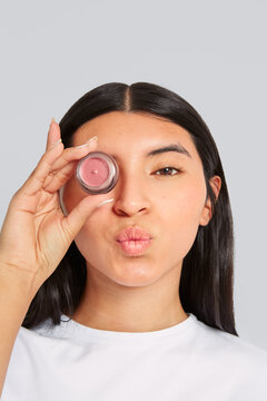 Woman posing with lip gloss covering one of her eyes
