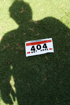404 marathon bib on grass with shadow of a runner near it