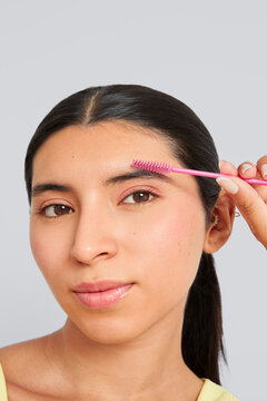 Woman combing shaping eyebrow with spoolie brush