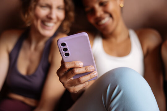 Friends Laughing Together While Looking At Smartphone