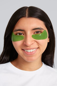 Woman smiling while wearing moisturizing patches under her eyes.