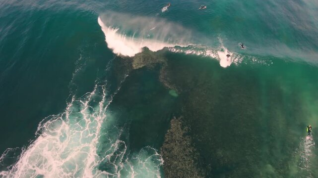 Aerial drone view of surfers, surfing paddling, duck diving, with beautiful blue collars and glass sea
