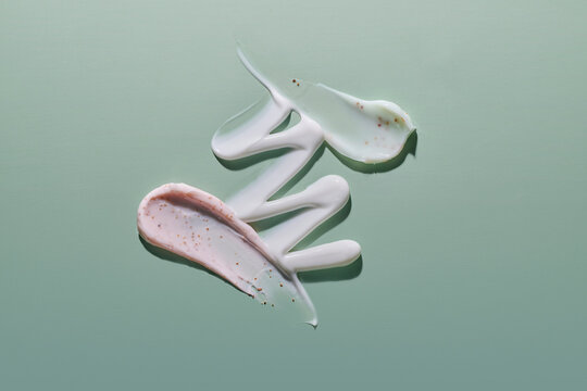Swirls of cosmetic creams and scrubs artfully arranged on a green