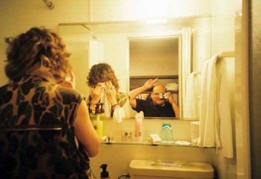 Couple in bathroom mirror taking photo with peace sign