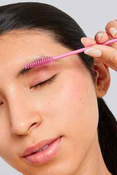 Woman combing her natural eyebrows with a brush.