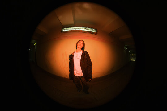 Person Stands in Dimly Lit Space With Orange Background Light
