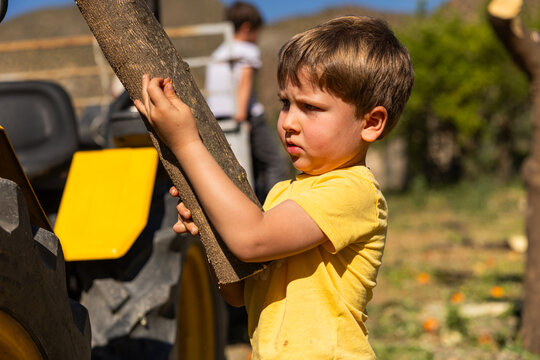 Young boy carrying wood log working outdoors
