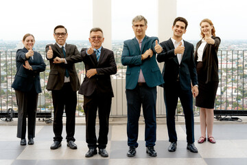 Obraz premium Group of diverse multiethnic corporate business people standing in a row on an office rooftop balcony and showing thumbs up with happy smiles for team achievement