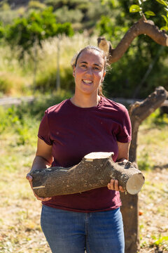 Woman holding cut log after tree pruning