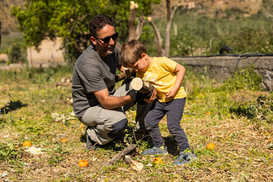 Father and son bonding outdoors, moving wood logs