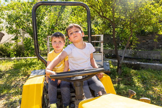 Two young brothers playing on a tractor outdoors