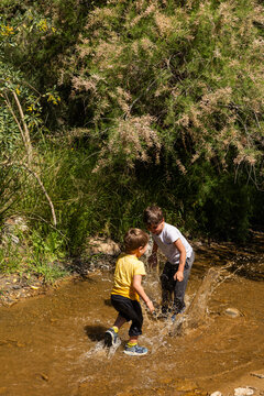 Children splashing and playing in nature stream