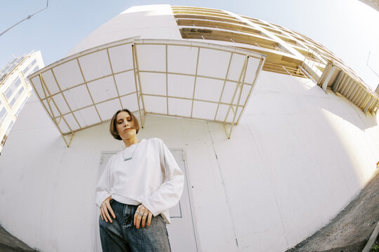 Young Woman Poses Near Modern Building in Urban Setting