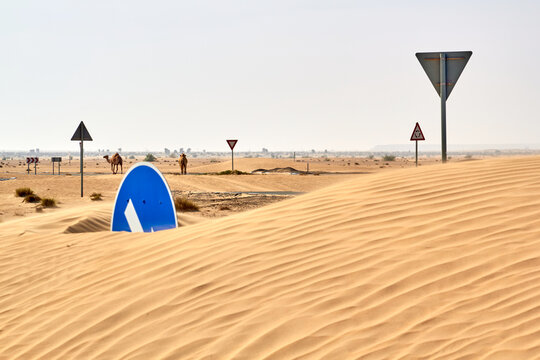 Roundabout road traffic circle signs buried under desert sand dune