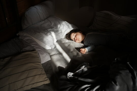 Child Sleeps on Bed in Soft Light During Morning Hours