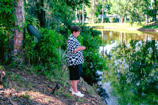  fishing by a calm pond in a lush green park.