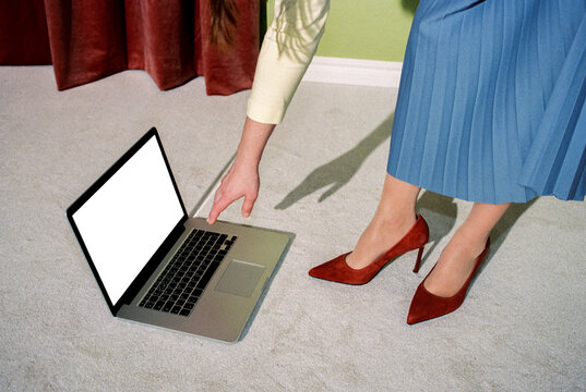 Woman in Red Heels Reaching for Laptop Placed on Floor
