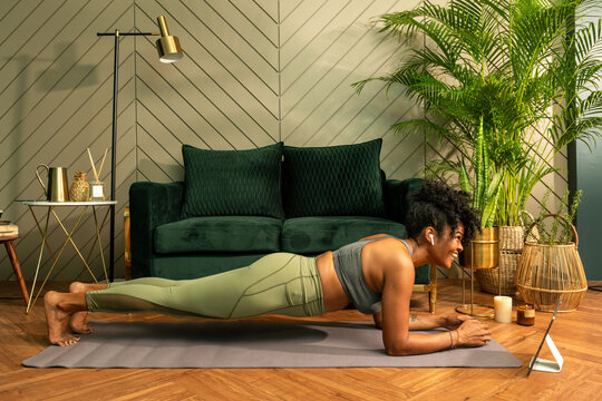 Woman doing a plank exercise in a stylish living room setting.