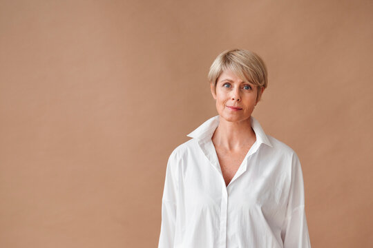 Confident Woman in a Crisp White Shirt Against a Warm Backdrop