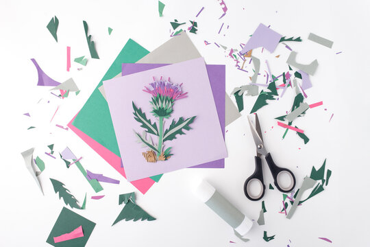 Handcrafted paper flower with adhesive stick, cutting tools, blank sheets on white backdrop. Ideal for creative blogs, online craft tutorials, digital publishing, primary education websites