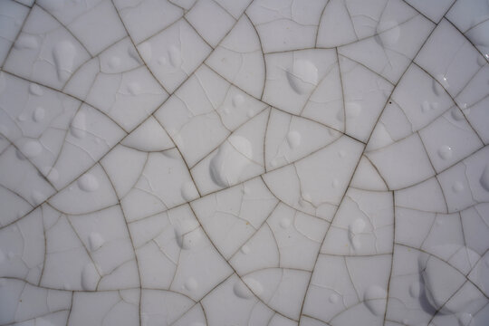 Cracked white ceramic glaze texture with water droplets, detailed macro background