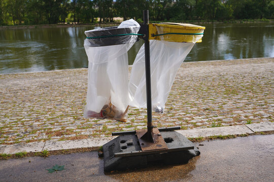 Outdoor public waste bins with plastic bags on a riverside embankment in France