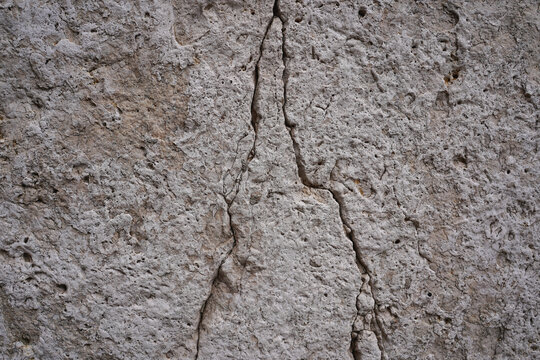 Weathered grey stone wall texture with a prominent vertical crack in Orleans France