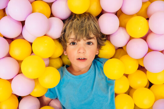 Top view of young boy playing in colorful ball pit