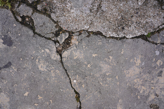 Cracked concrete surface texture with weathered grey tones and urban debris