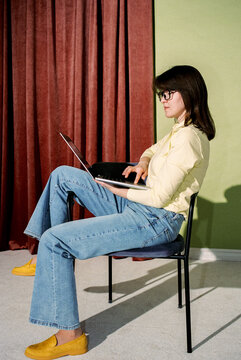 Woman Sitting on Chair Using Laptop in Minimalist Interior